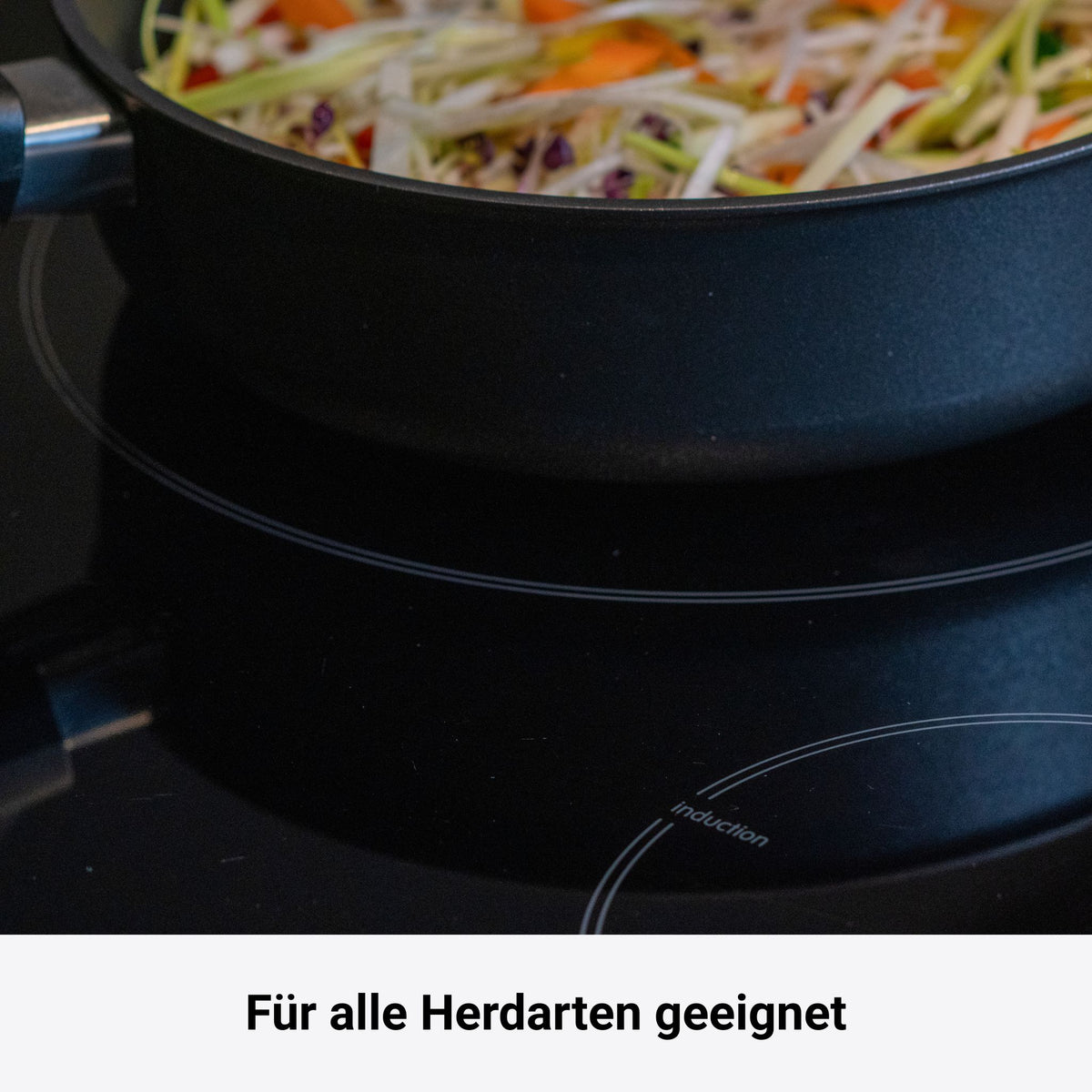 Runde schwarze Tepanyaki Pfanne mit Edelstahlgriff und angebratenem Gemüse.