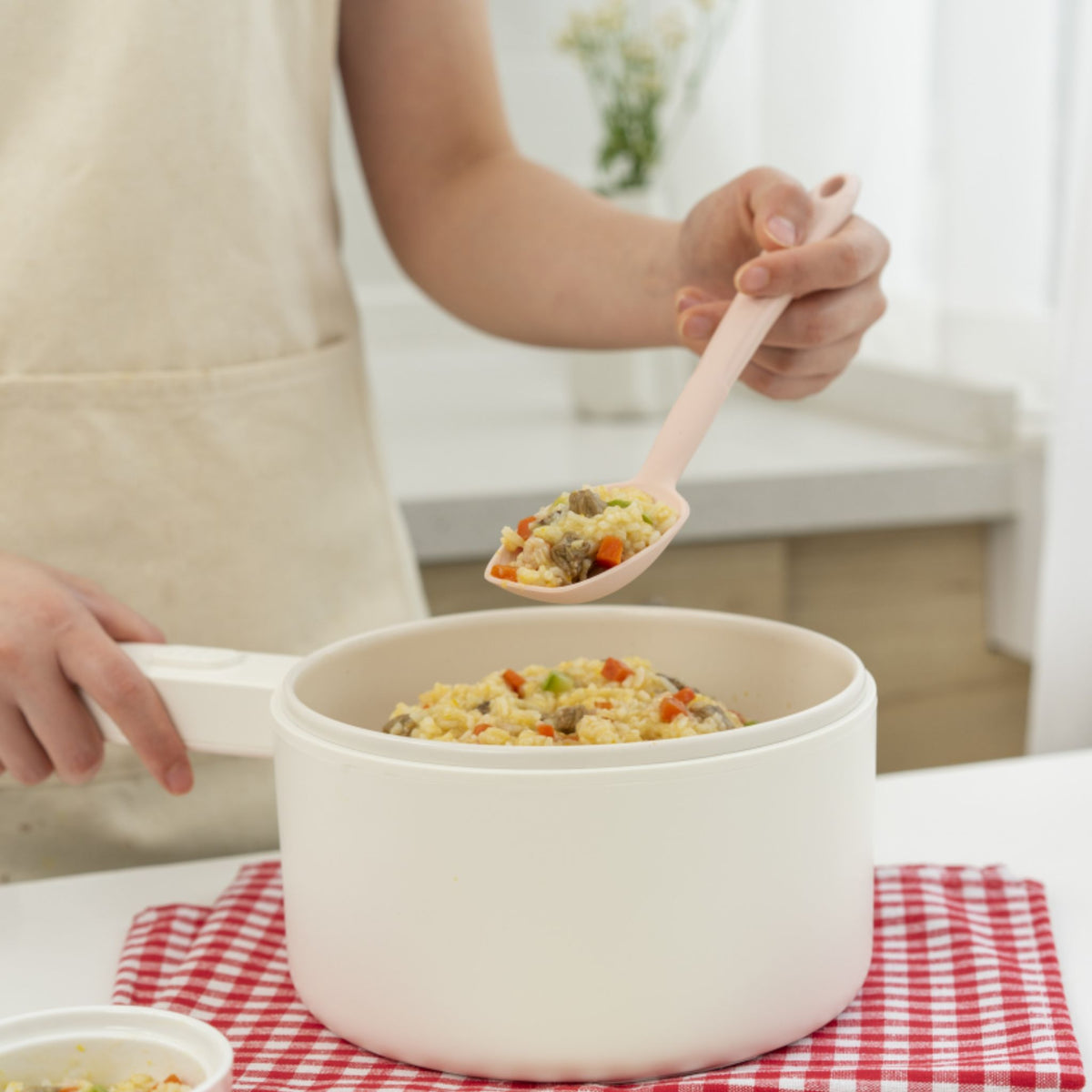 Soßenlöffel in Altrosa mit rundem Löffelkopf und ergonomischem Griff beim Servieren aus weißem Topf.