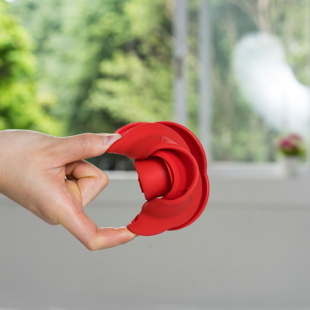 Roter, zusammenklappbarer Trichter aus flexiblem Silikon, handlich gehalten.