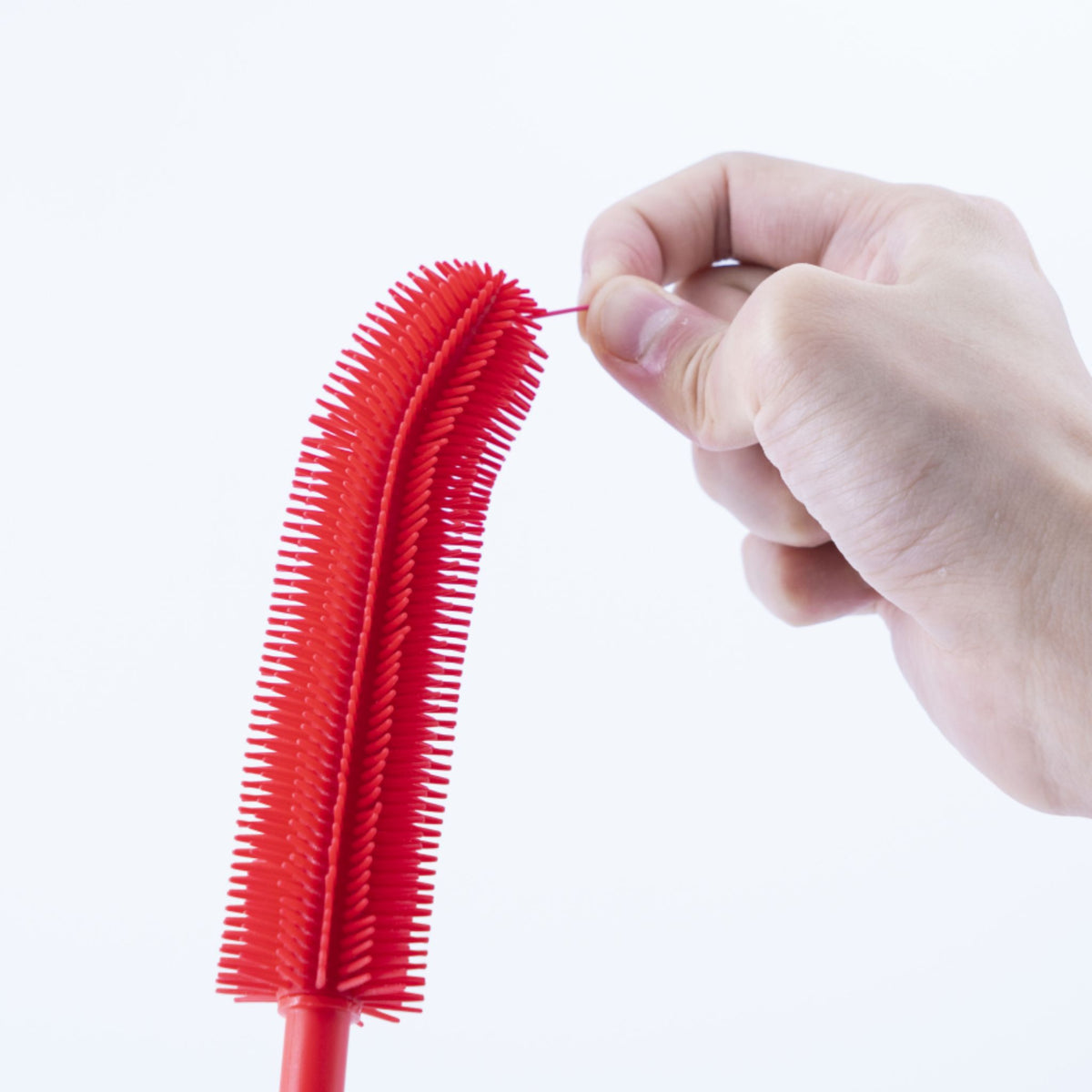 Rote dünne Flaschenbürste mit flexiblen Borsten und gebogenem Griff in Hand gehalten.