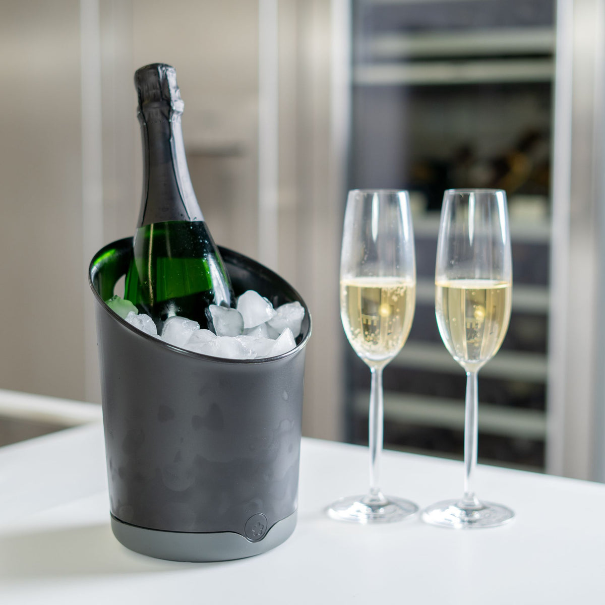 Schwarzer Utensilienbehälter als Eiswürbeleimer mit Sektflasche und zwei Sektgläsern.
