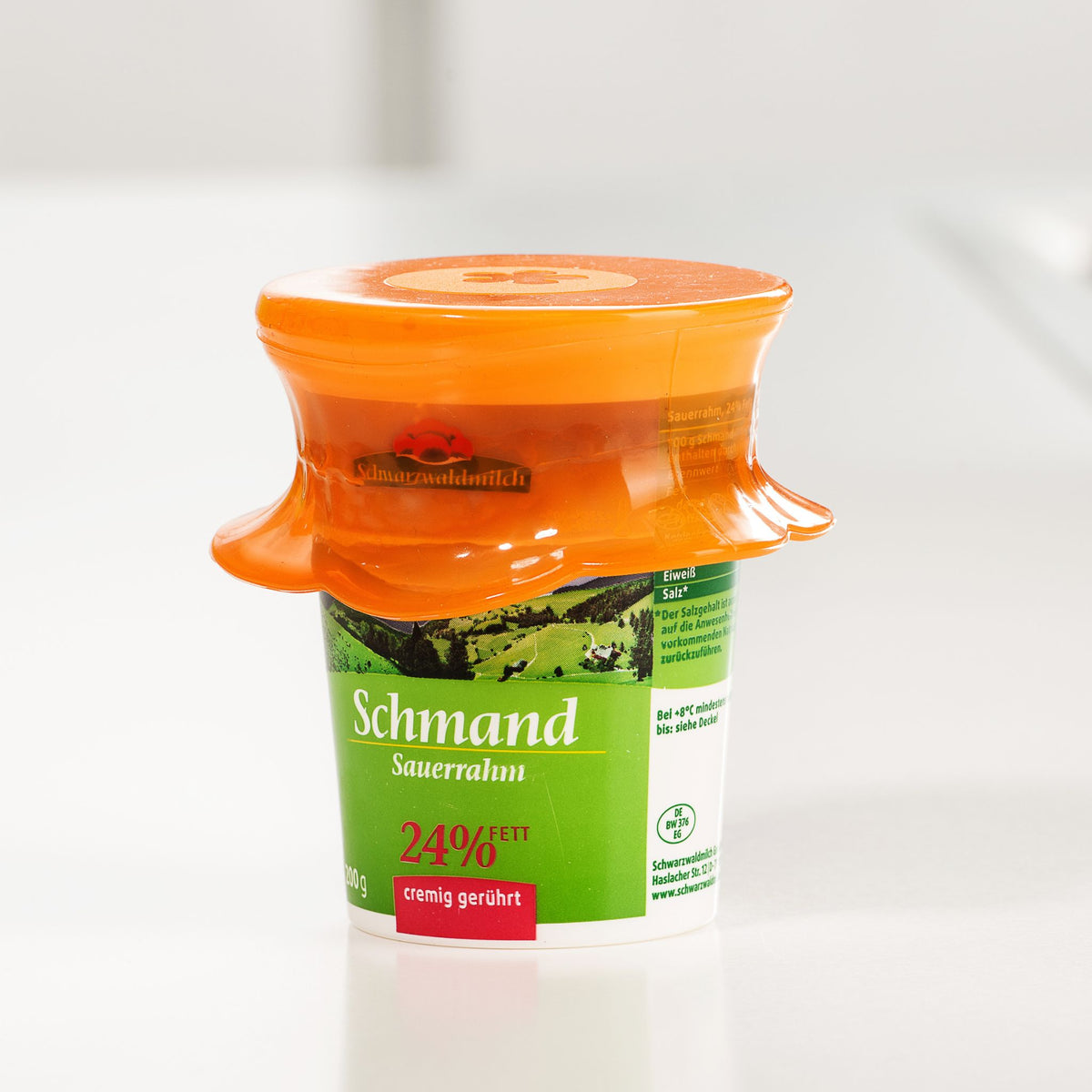 Oranger flexibler Deckel auf grünem Becher für Schmand mit 24% Fettgehalt.