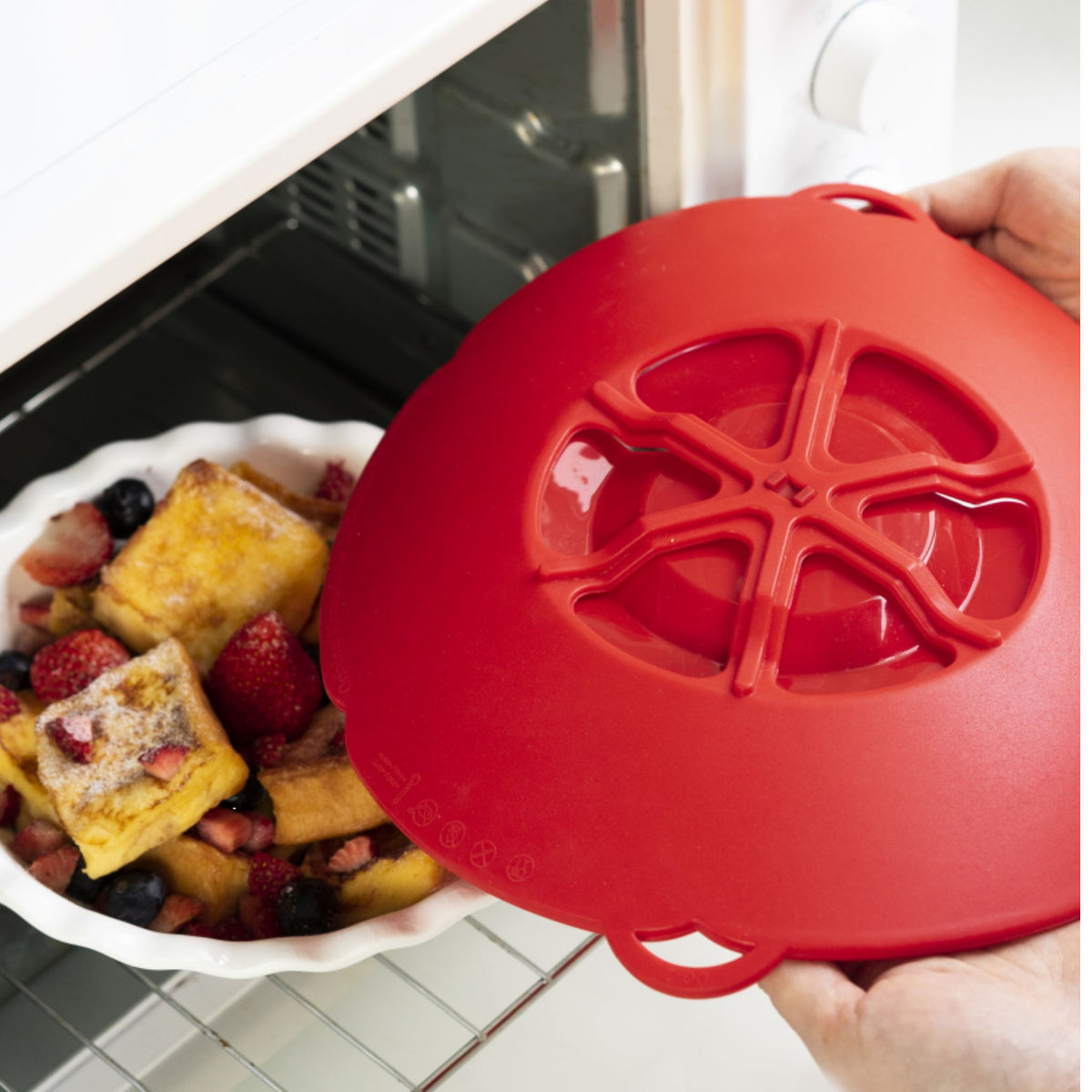 Rote Kochblume aus flexiblem Silikon auf einer Auflaufform im Backofen.