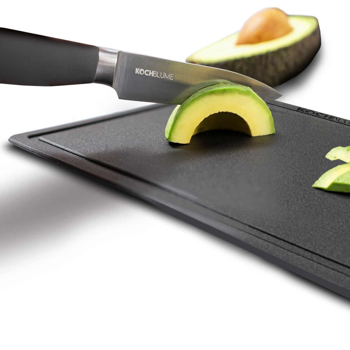 Gemüsemesser mit schwarzem Griff schneidet Avocado auf schwarzem Schneidebrett.