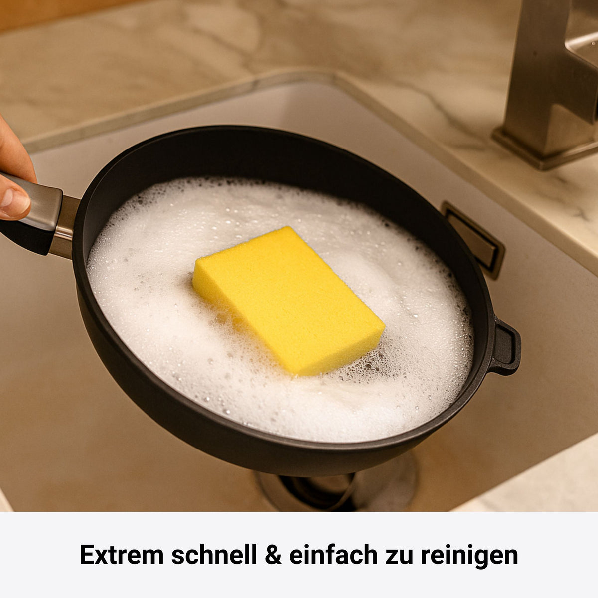 Schwarze Viereckpfanne mit abnehmbarem Griff, gefüllt mit Seifenlauge und gelbem Schwamm.