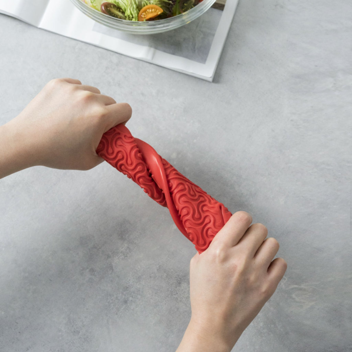 Roter Ofenhandschuh aus strukturiertem Silikon, gehalten von zwei Händen.