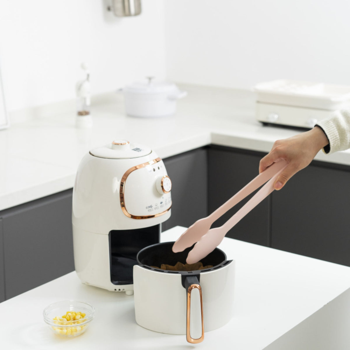 Anthrazitfarbene Grillzange mit ergonomischem Griff, gehalten über einem weißen Topf.
