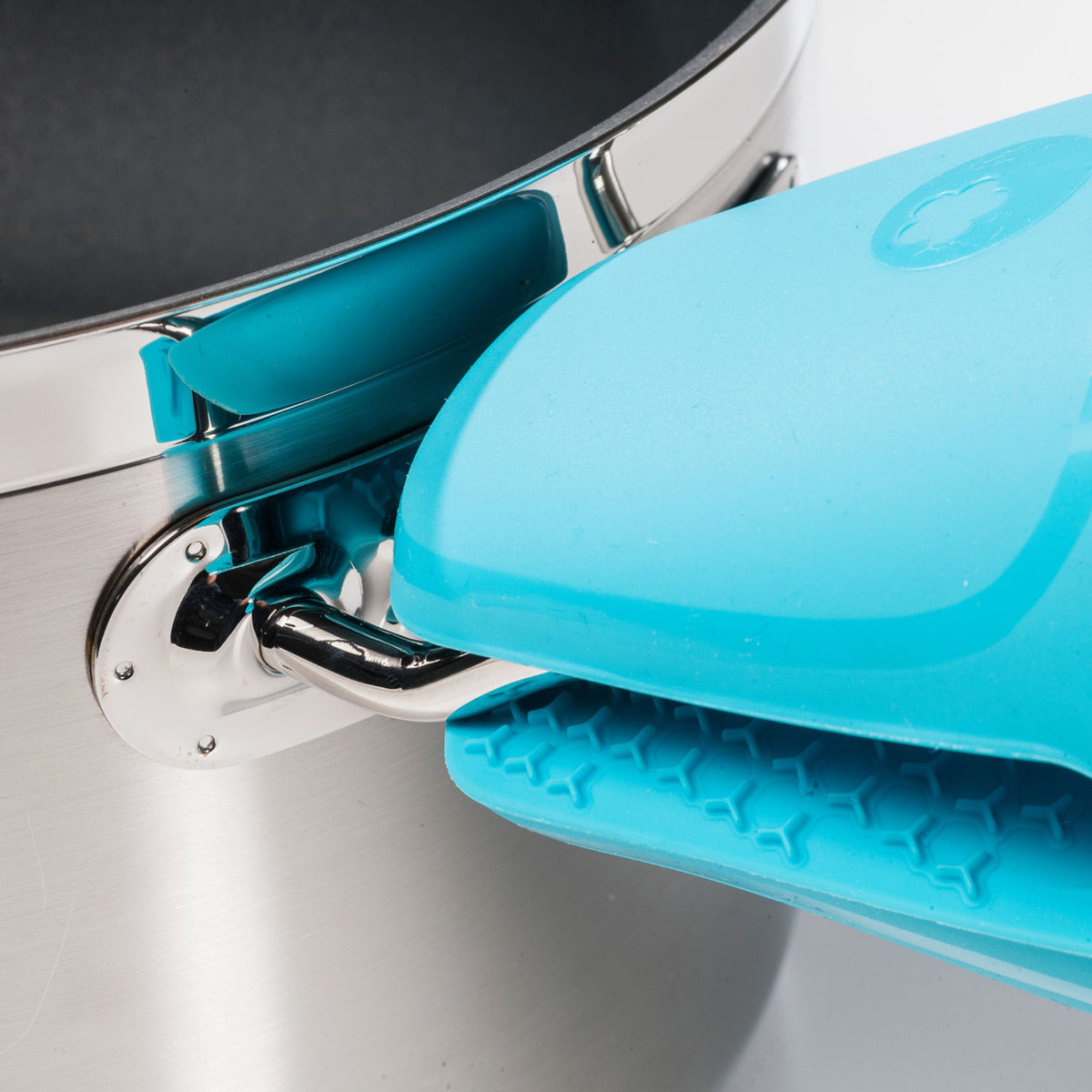 Blauer Thermo-Fingerschutz aus Silikon an Edelstahlpfanne befestigt.