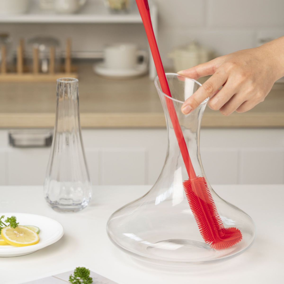 Rote dünne Flaschenbürste mit flexiblem Griff in klarer Glasflasche stehend.