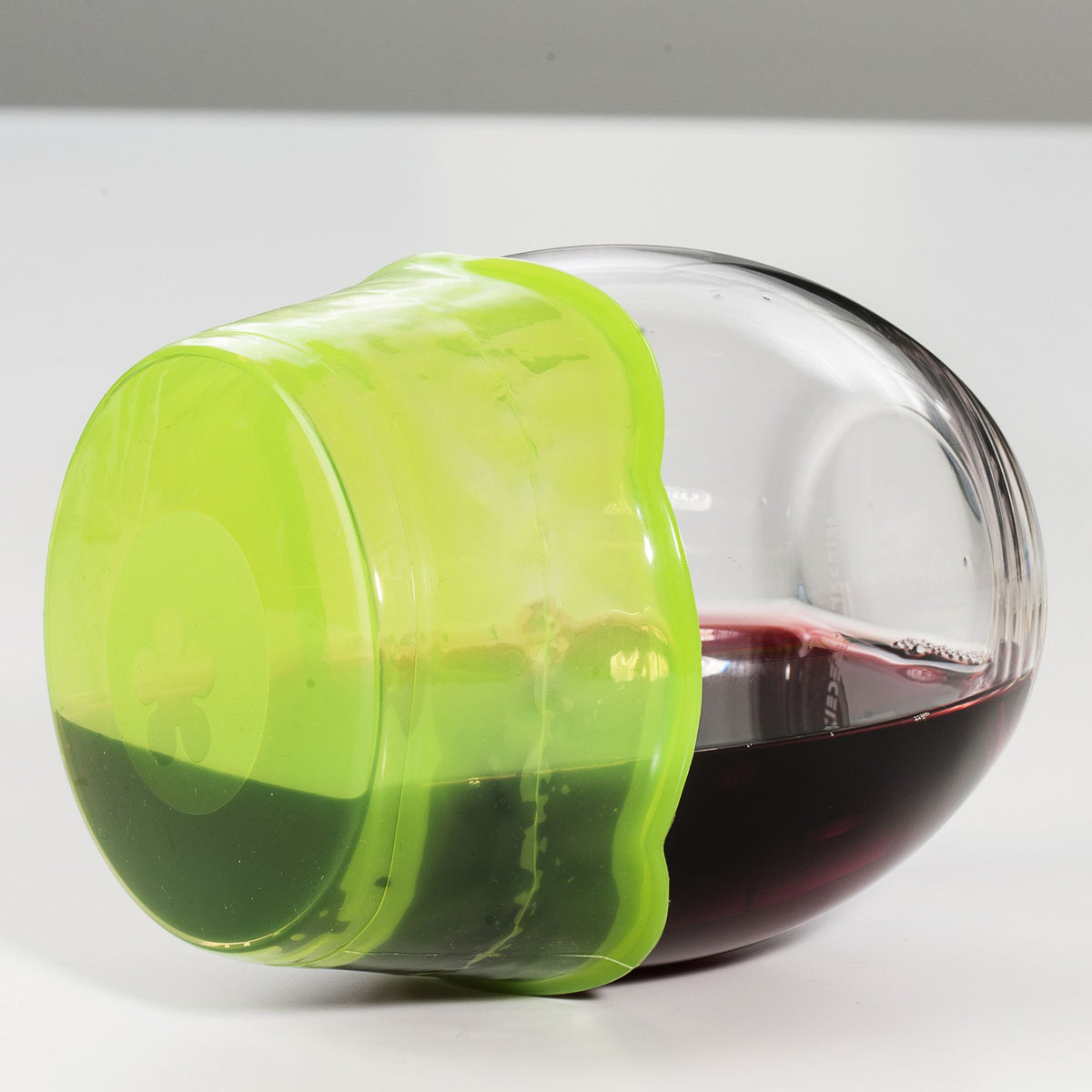Transparentes Glas mit limettengrünem flexiblen Deckel, gefüllt mit rotem Flüssigkeitsspuren.