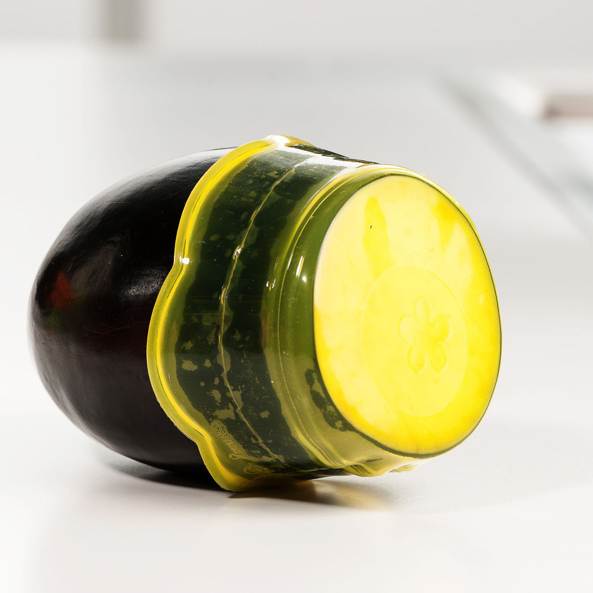 Schwarze Aubergine mit transparentem, limettengrünem Silikondeckel zum Frischhalten.