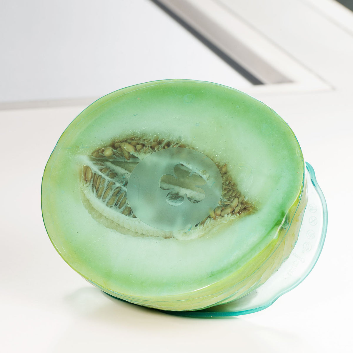 Halbierte grüne Honigmelone mit sichtbarem Fruchtfleisch auf weißer Oberfläche.