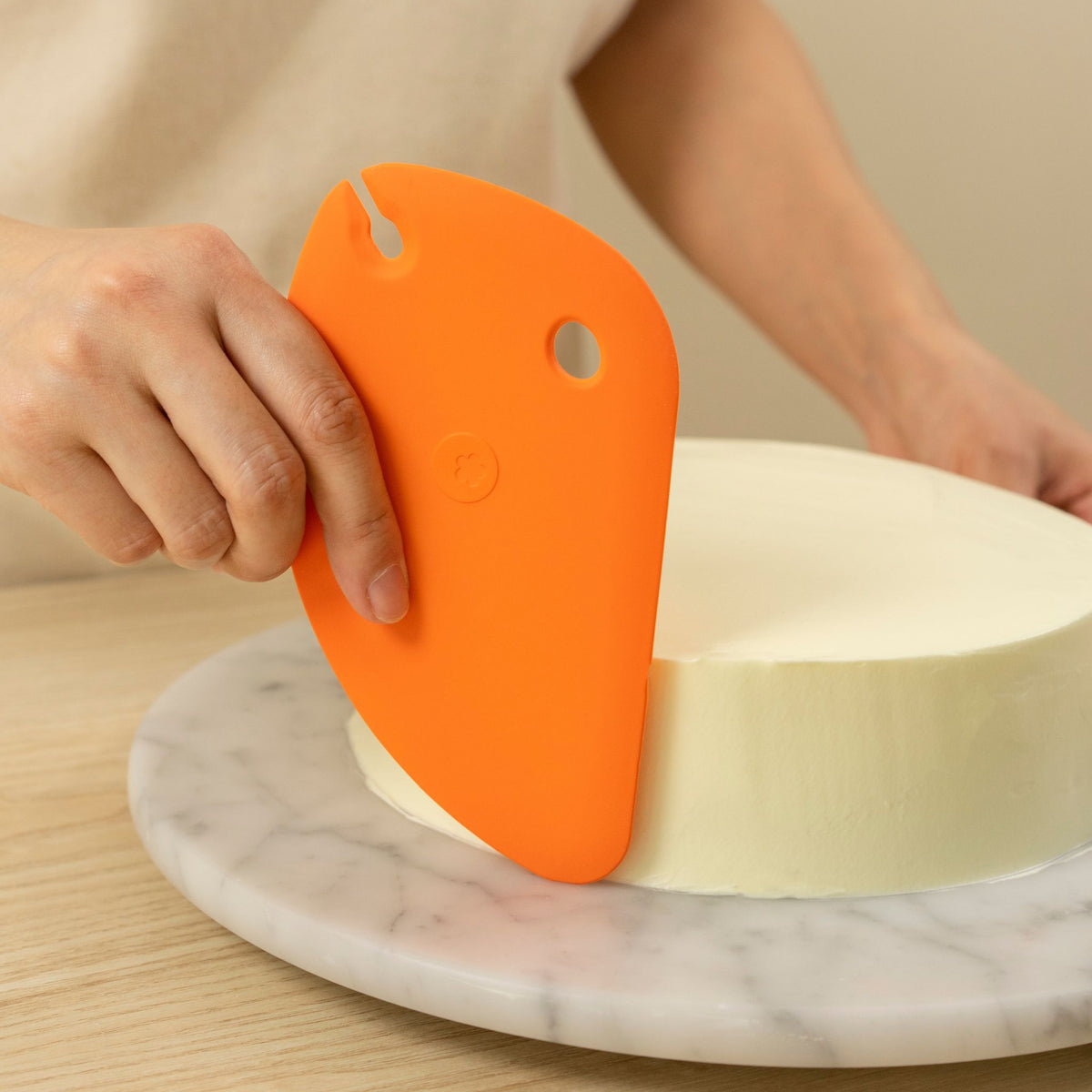 Anthrazitfarbene Teigkarte aus flexiblem Material in Anwendung auf runder Kuchenplatte aus Marmor.