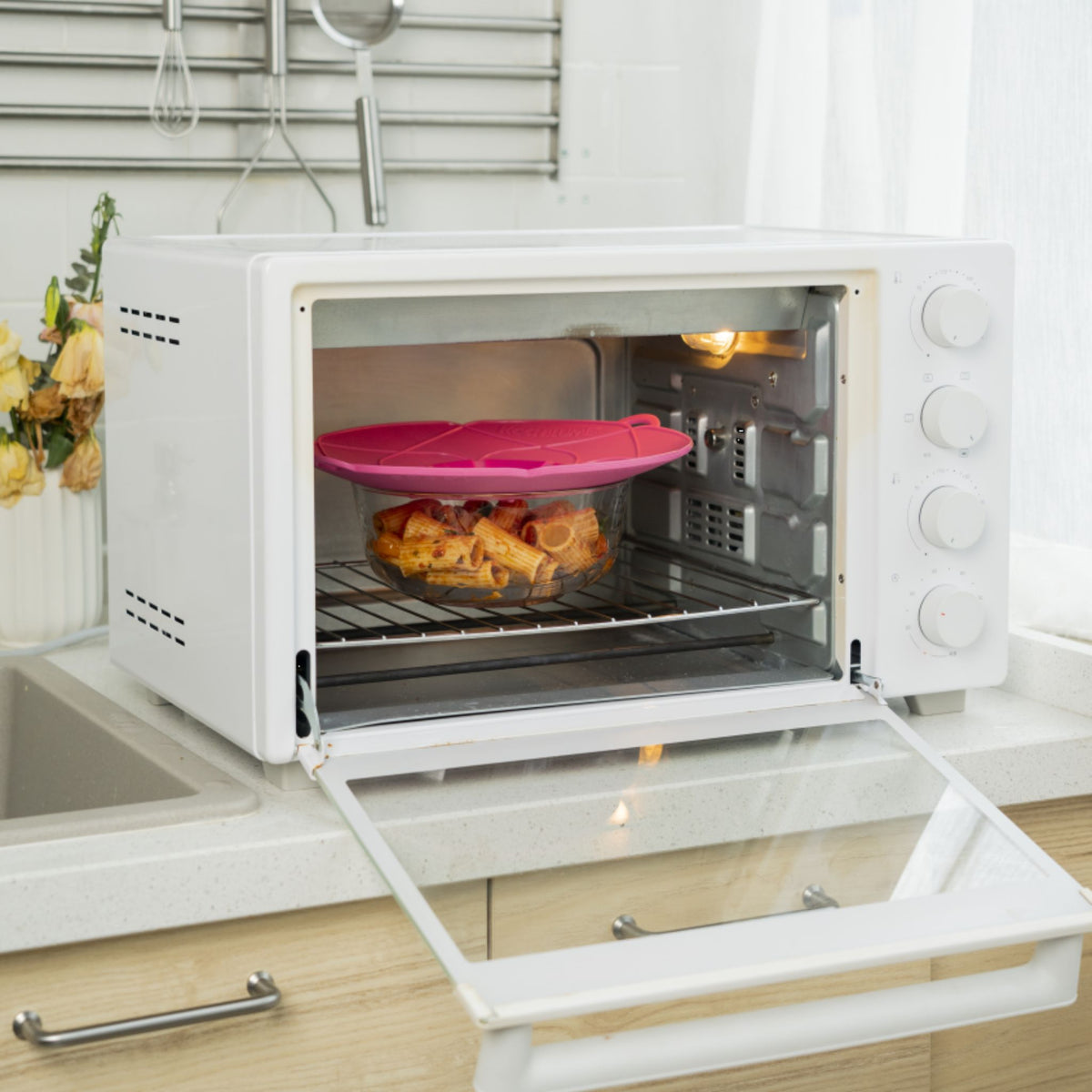 Anthrazitfarbene Kochblume als Deckel auf Backofen mit frisch gebackenem Gebäck darunter.