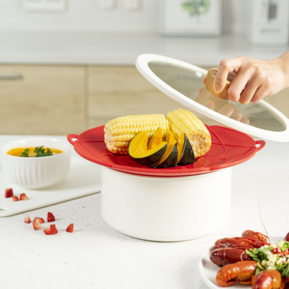 Rote Kochblume XL Dampfgareraufsatz mit Mais und Kürbis auf weißem Topf und Glasdeckel.