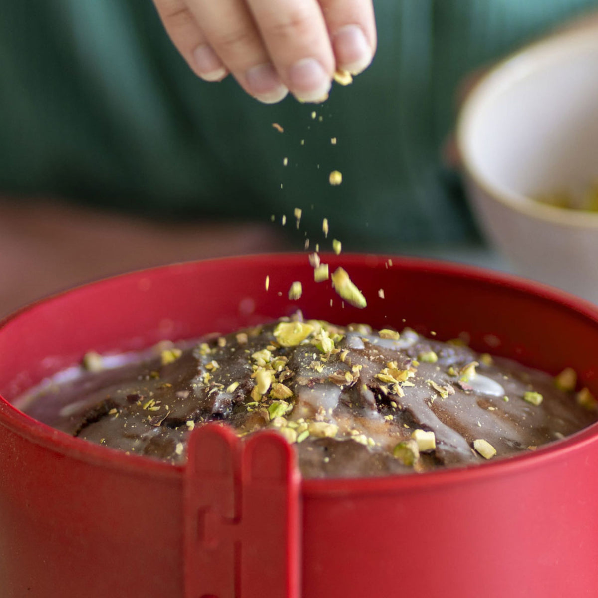 Rote Springform mit Schokoladentorte und Nussstücken darin.